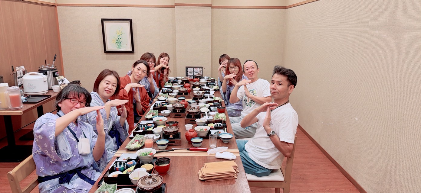合宿で食卓を囲み、笑顔で写真を撮る仲間たち